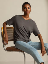 Woman wearing a charcoal silk V-neck T-shirt with light blue jeans