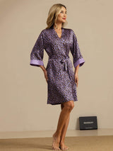 Woman wearing purple leopard print silk knee-length kimono robe with belted waist and 3/4 sleeves
