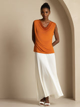 Orange sleeveless silk cowl neck top styled with white skirt for casual wear
