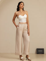 White silk camisole with beige high-waist full-length straight-leg pants with pockets