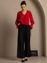 Model wearing red silk-wool blouse and black straight-leg pants with drawstring waist