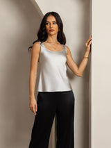 Model wearing silver sleeveless silk U-neck tank top with straight fit