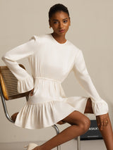 Model wearing a white silk ruffle sleeve A-line dress with long sleeves and flowy hem