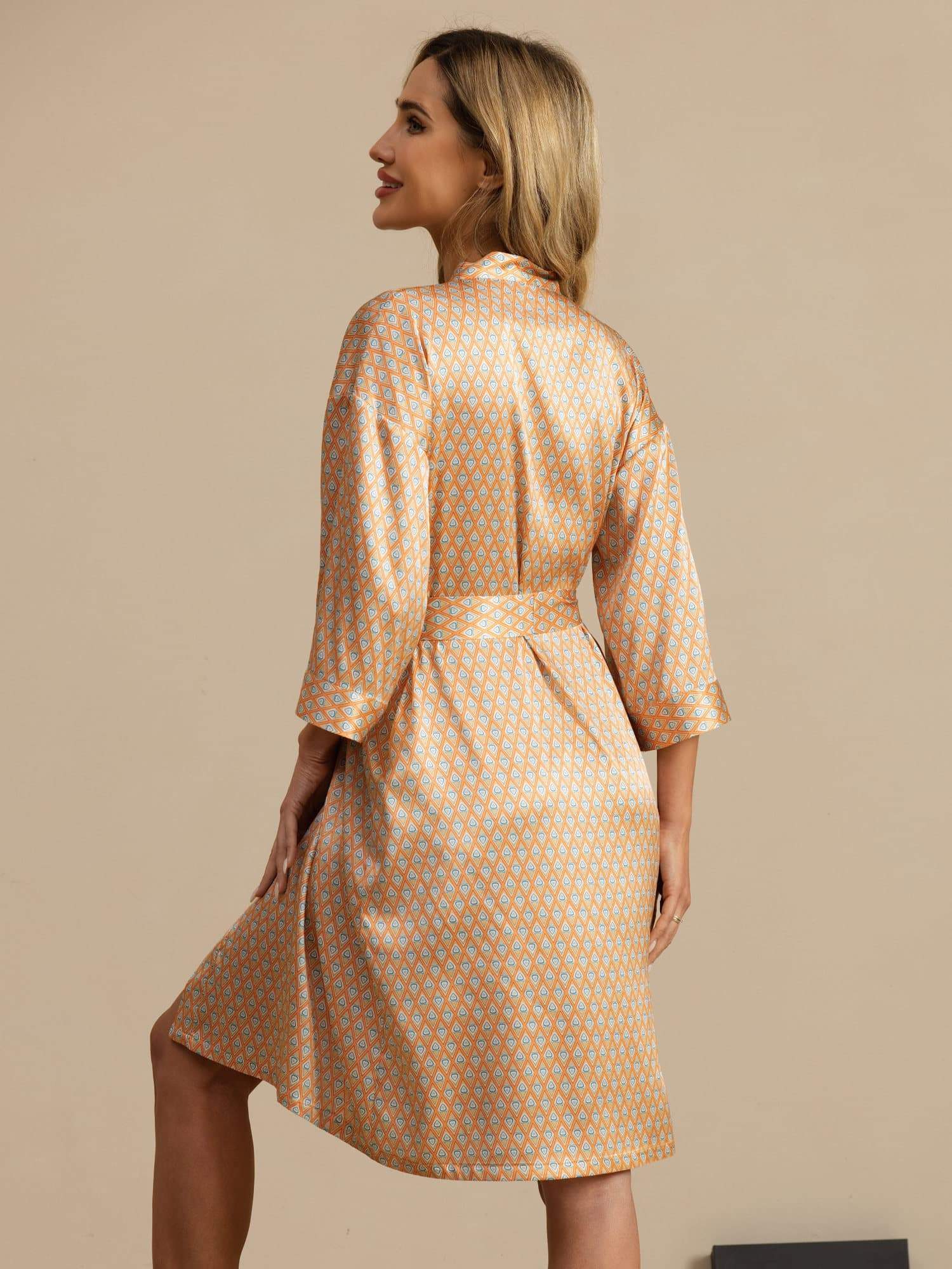 Woman wearing orange heart geo printed silk knee-length kimono robe with belted waist