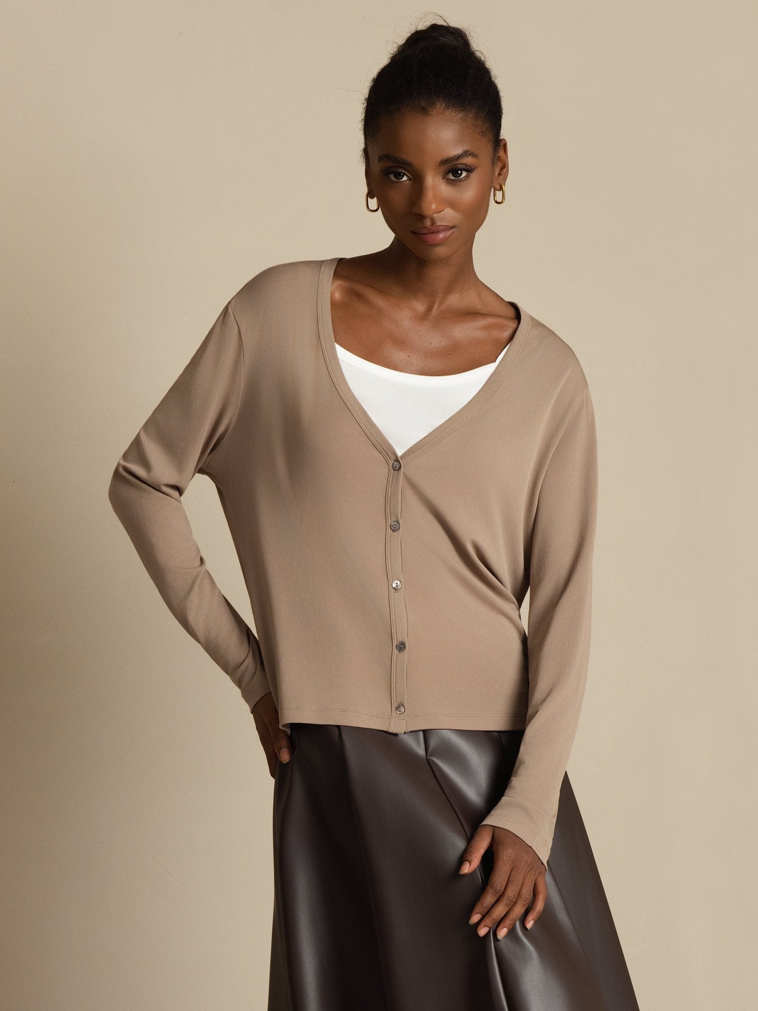 Woman wearing a beige silk V-neck long sleeve button-front cardigan