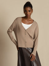 Woman wearing a beige silk V-neck long sleeve button-front cardigan