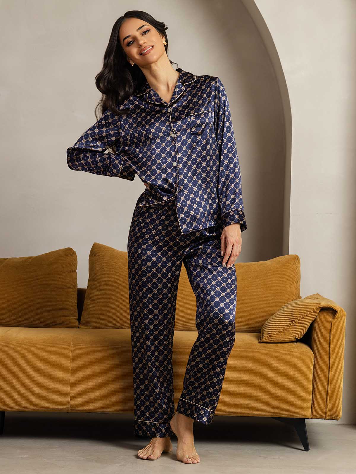 Woman wearing navy silk pajamas set with gold chain print, notch collar and piping