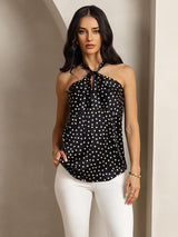 Black polka dot silk halter top with twist front and keyhole back, worn with white pants