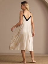 Back view of cream silk midi nightgown with black contrast V-neck and spaghetti straps