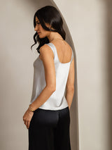 White silk sleeveless U-neck women's tank top with straight fit and low back, model wearing black pants