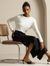 Woman wearing white long-sleeve top with black silk wide-leg split pants