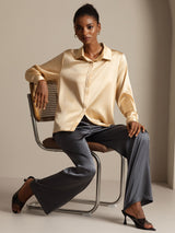 Woman wearing champagne silk long sleeve lapel collar blouse with black pants
