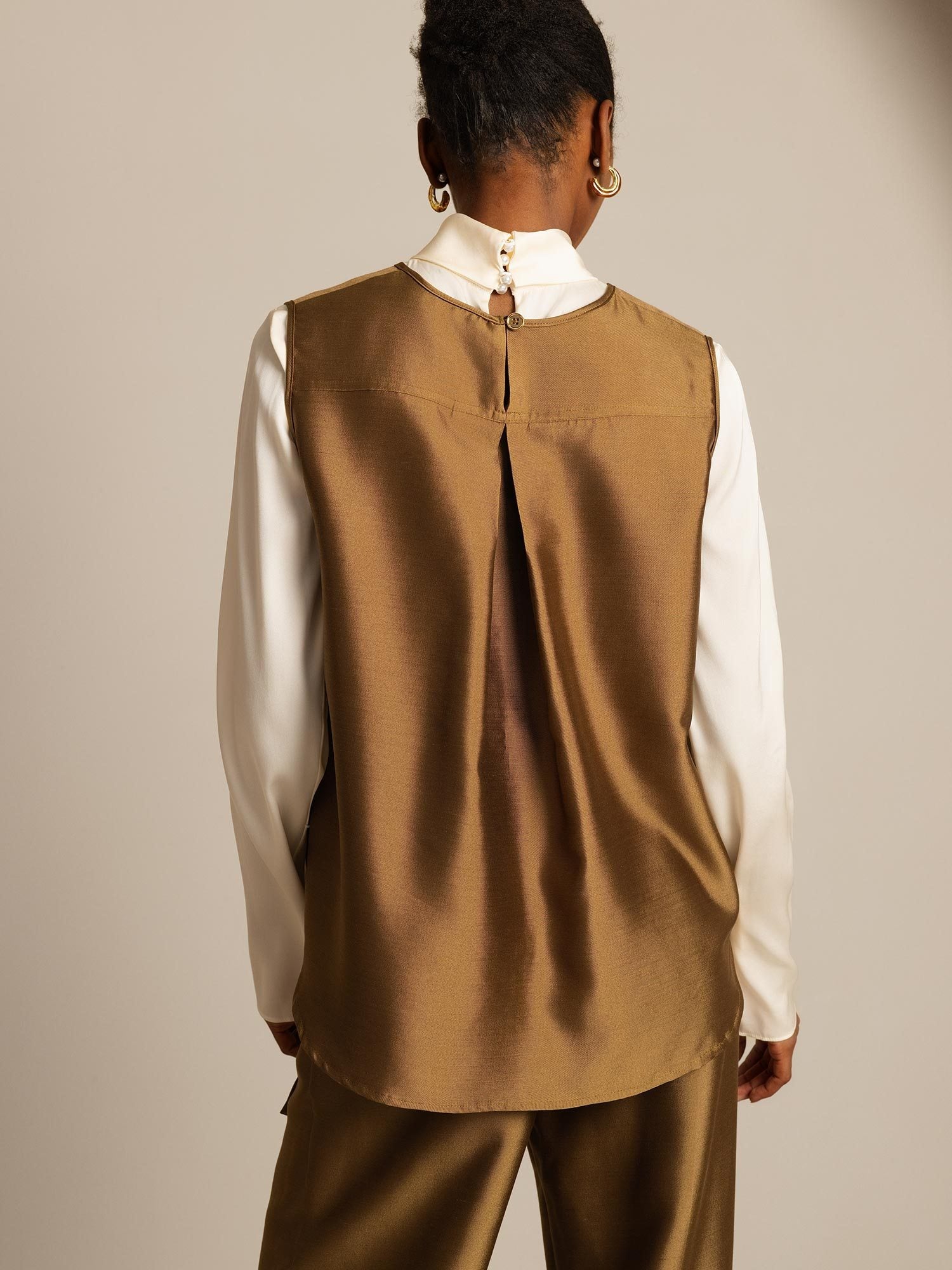 Back view of brown silk-wool women’s vest with button closure, layered over a white blouse