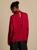 Back view of a red silk turtleneck blouse with keyhole closure