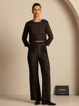 Model wearing black textured grid silk wide-leg pants with matching sheer top