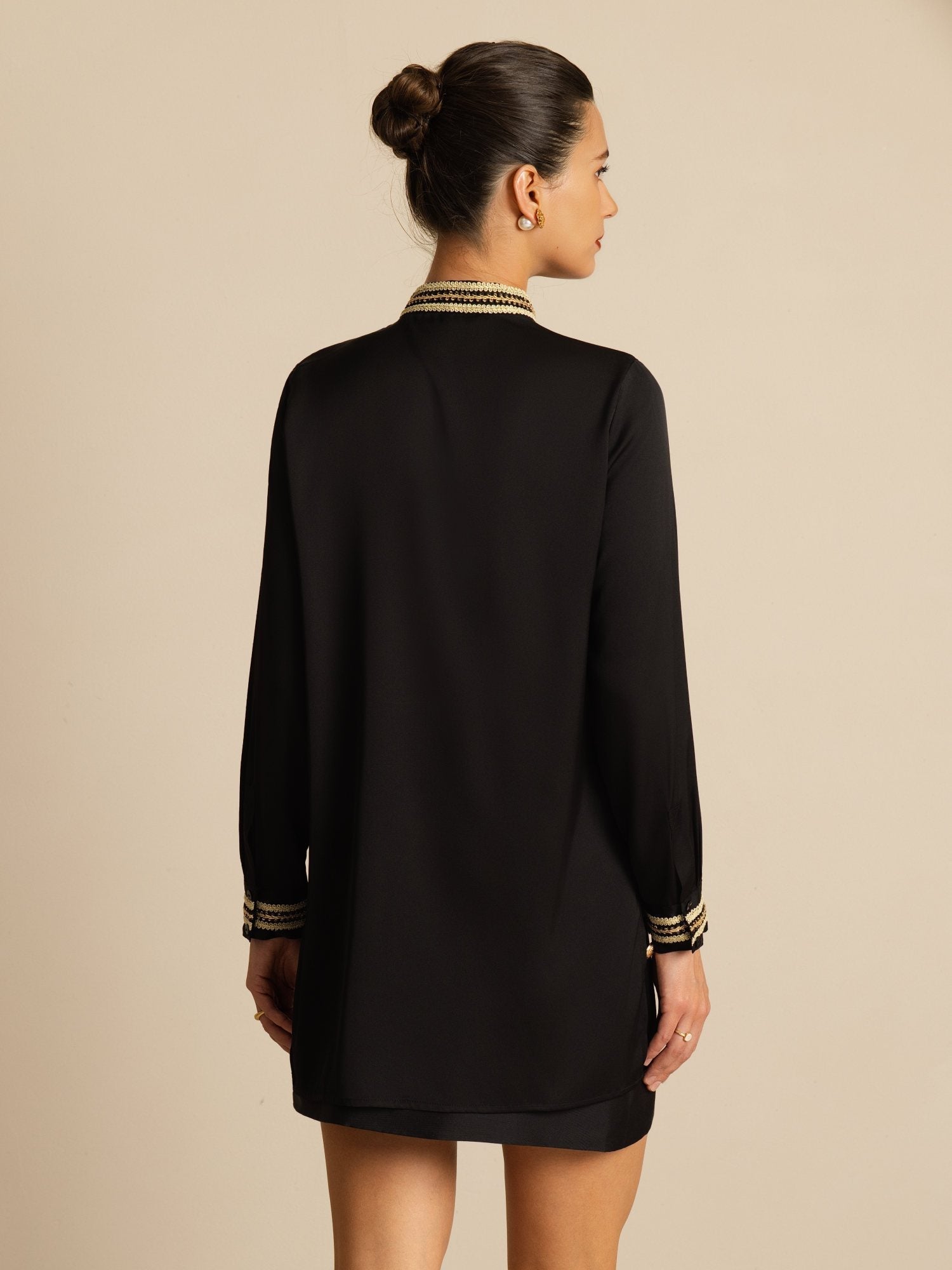 Black silk pleated stand collar blouse with contrast piping and long sleeves, back view