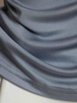 Close-up of blue-gray pure silk fabric with soft folds and stitched hem