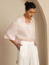 Model wearing blush silk cropped blouse with lapel collar and drawstring hem
