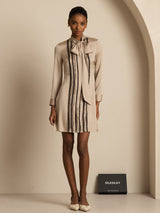 Beige silk tie-neck short shirt dress with vertical pleats and long sleeves