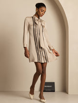 Beige silk tie-neck short shirt dress with vertical pleats and long sleeves