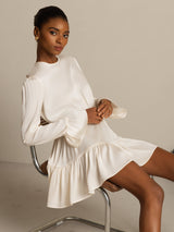 Model wearing ivory silk A-line dress with ruffle sleeves and hem