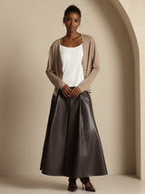 Model wearing beige silk V-neck long sleeve cardigan with white tank top and dark skirt