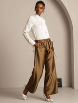 Model wearing brown silk-wool straight-leg pants with drawstring waist and side pockets
