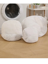 White mesh laundry wash bags for delicate silk garments beside a washing machine