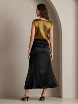 Model wearing gold sleeveless silk tank top with black midi skirt, back view