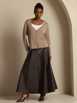 Model wearing beige V-neck long sleeve silk cardigan with button front, styled with dark skirt