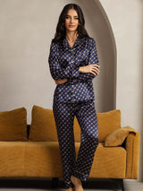 Model wearing navy pure silk chain print long sleeve pajama set with notched collar and piping trim