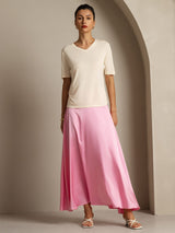 Woman wearing a cream pure silk V-neck T-shirt with a pink satin skirt