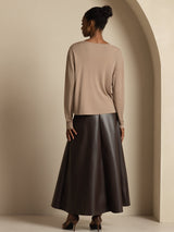 Back view of a woman wearing a beige long-sleeve silk cardigan with a dark maxi skirt