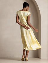 Model wearing a pale yellow silk midi dress with round neck and cap sleeves