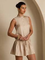 Model wearing beige sleeveless silk short dress with stand collar, button front and drawstring waist