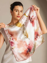 Woman holding 100% mulberry silk floral square scarf with pink trim