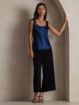 Navy sleeveless U-neck silk tank top with straight fit, styled with black wide-leg pants