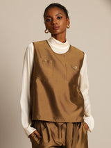 Model wearing brown silk-wool blend vest with button pockets over cream turtleneck
