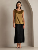 Model wears gold sleeveless round neck silk tank top with black skirt