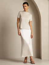 Model wearing a cream pure silk short sleeve mock neck women’s t-shirt with white skirt