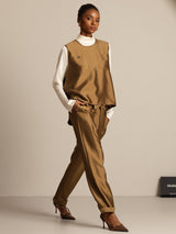 Model wearing brown silk-wool blend vest with button pocket design over white top and matching pants