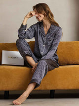 Woman wearing navy ginkgo print pure silk pajama set with notch collar and piping
