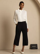 Woman wearing white silk stand collar bow blouse with long sleeves and black pants
