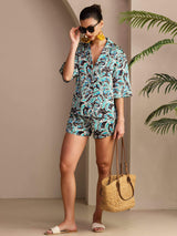 Woman wearing botanical print silk pajama set with short-sleeve button-up top and shorts