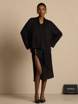 Black silk asymmetrical V-neck blouse with long sleeves and tie detail, styled with a slit skirt